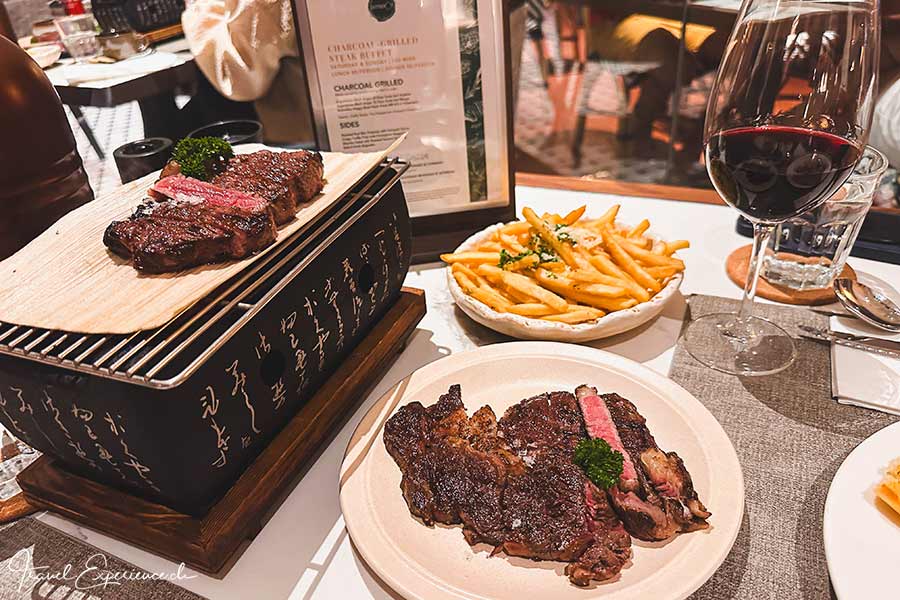 Tischgrill mit Fleisch, Pommes Frites und Weinglas im The Robertson House in Singapur