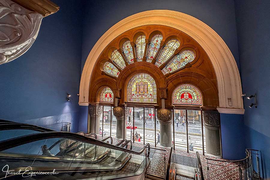 Ein-/Ausgang mit Rolltreppen und bunten Glasfenstern im Queen Victoria Building in Sydney